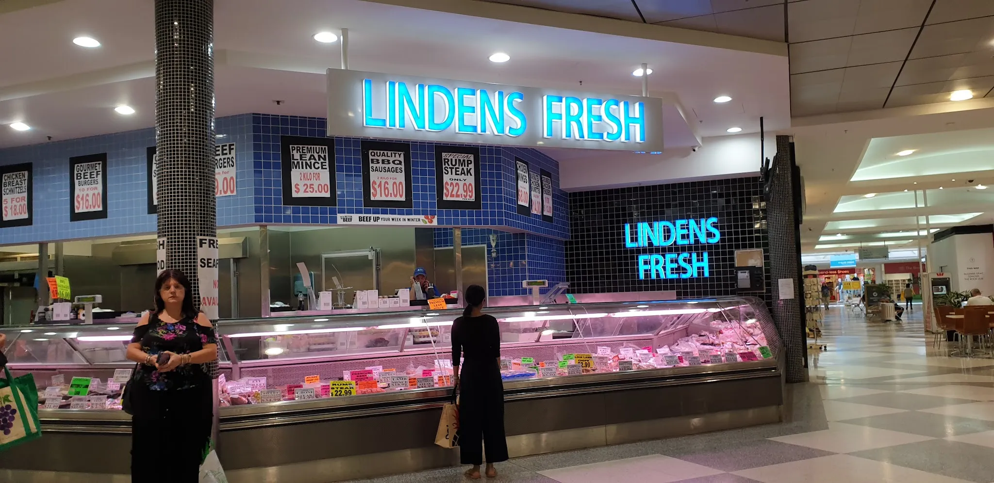 Lindens Fresh shopfront with bright cyan LED signage and customers at the counter at an earlier location, showing the history of the brand